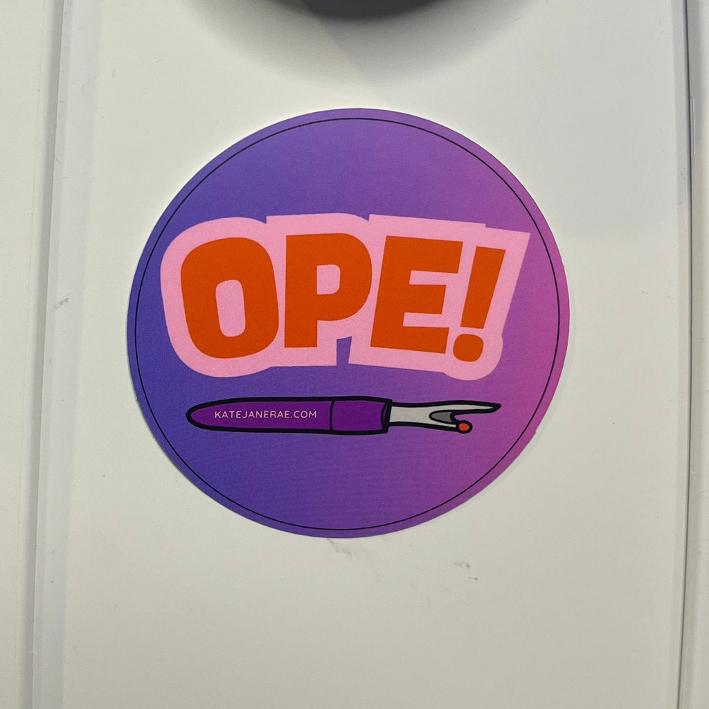 Close-up of a sewing machine with a 'OPE!' sticker on the control panel.