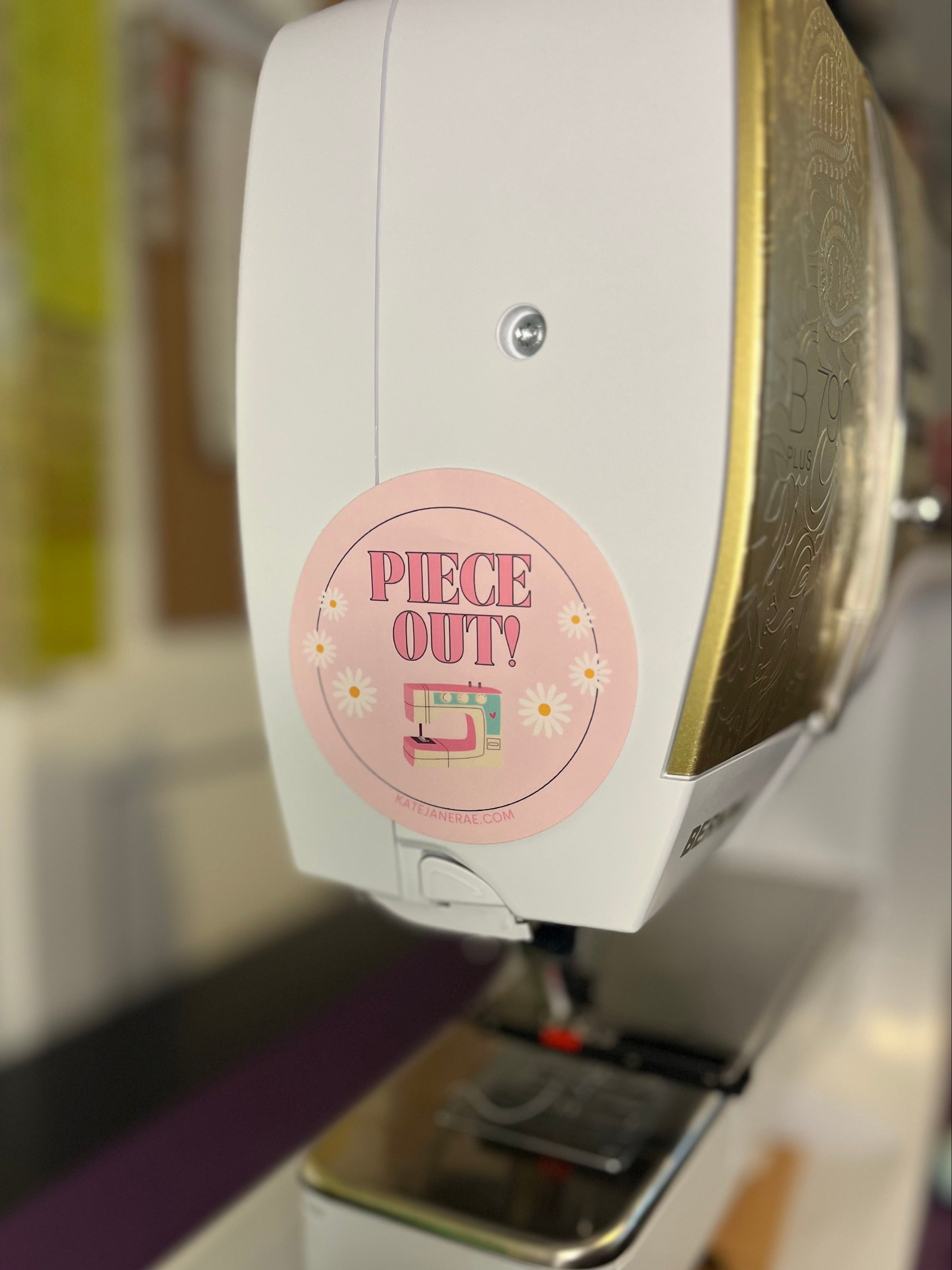 Sewing machine with a pink label reading 'Piece Outy' on a blurred background