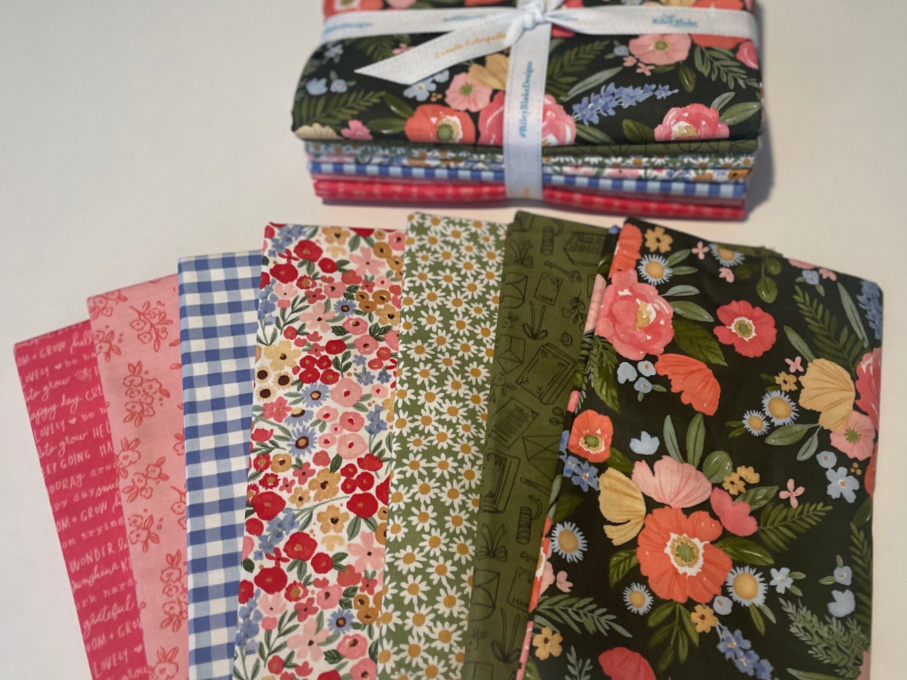 Collection of fabric bundles with floral and checkered patterns on a white background