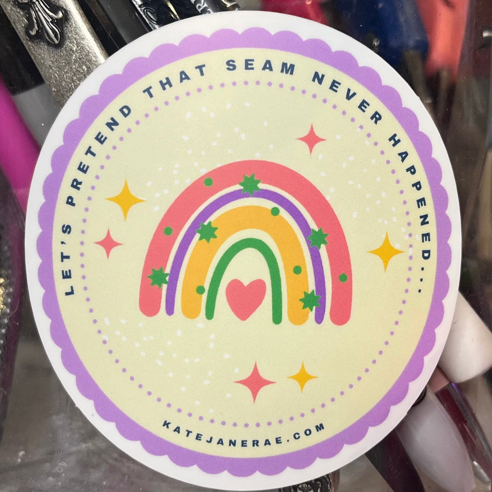 Crafting station with a jar of sewing supplies and a rainbow-themed sticker.