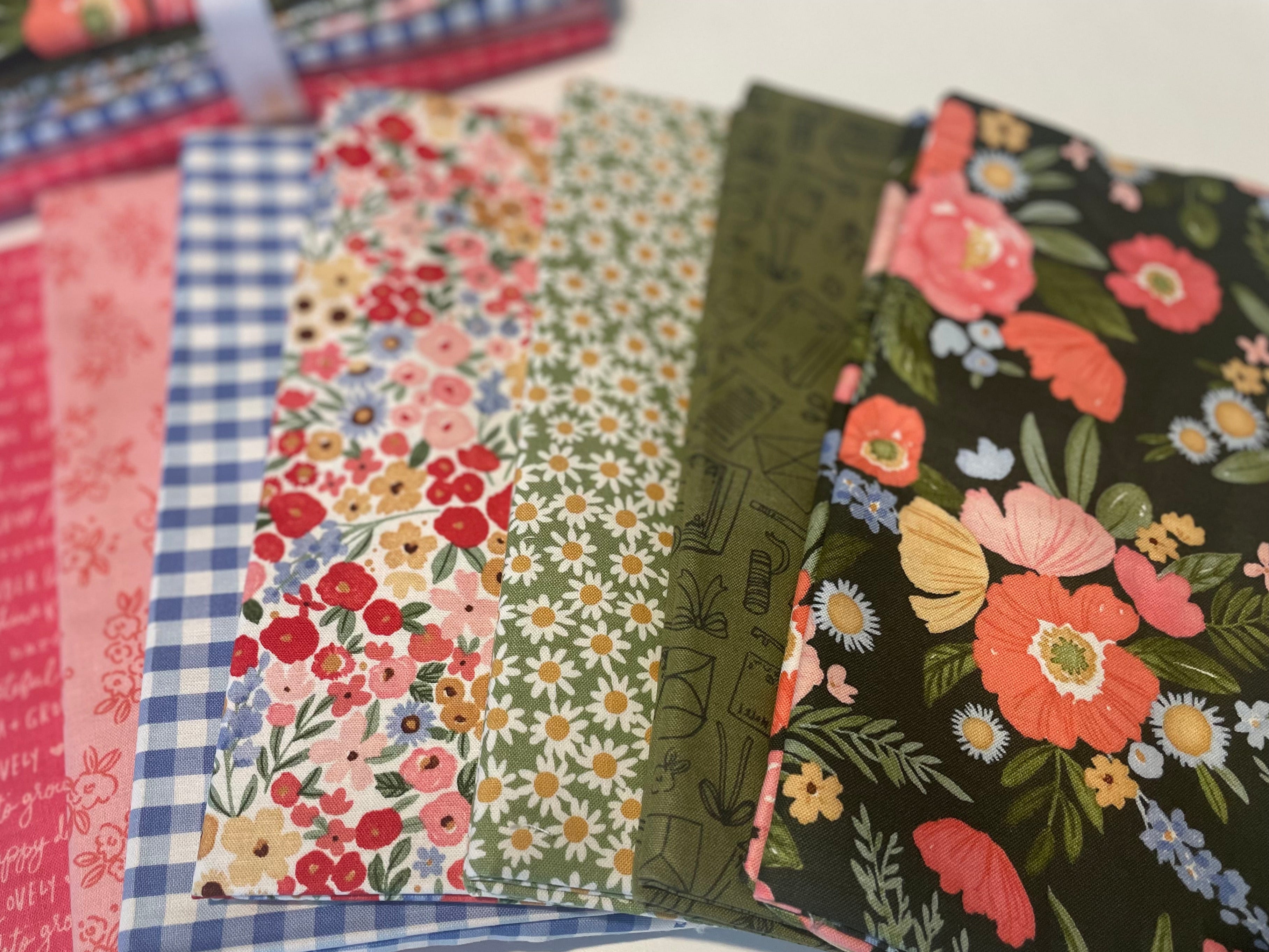 Stack of fabric swatches with floral and checkered patterns on a white background