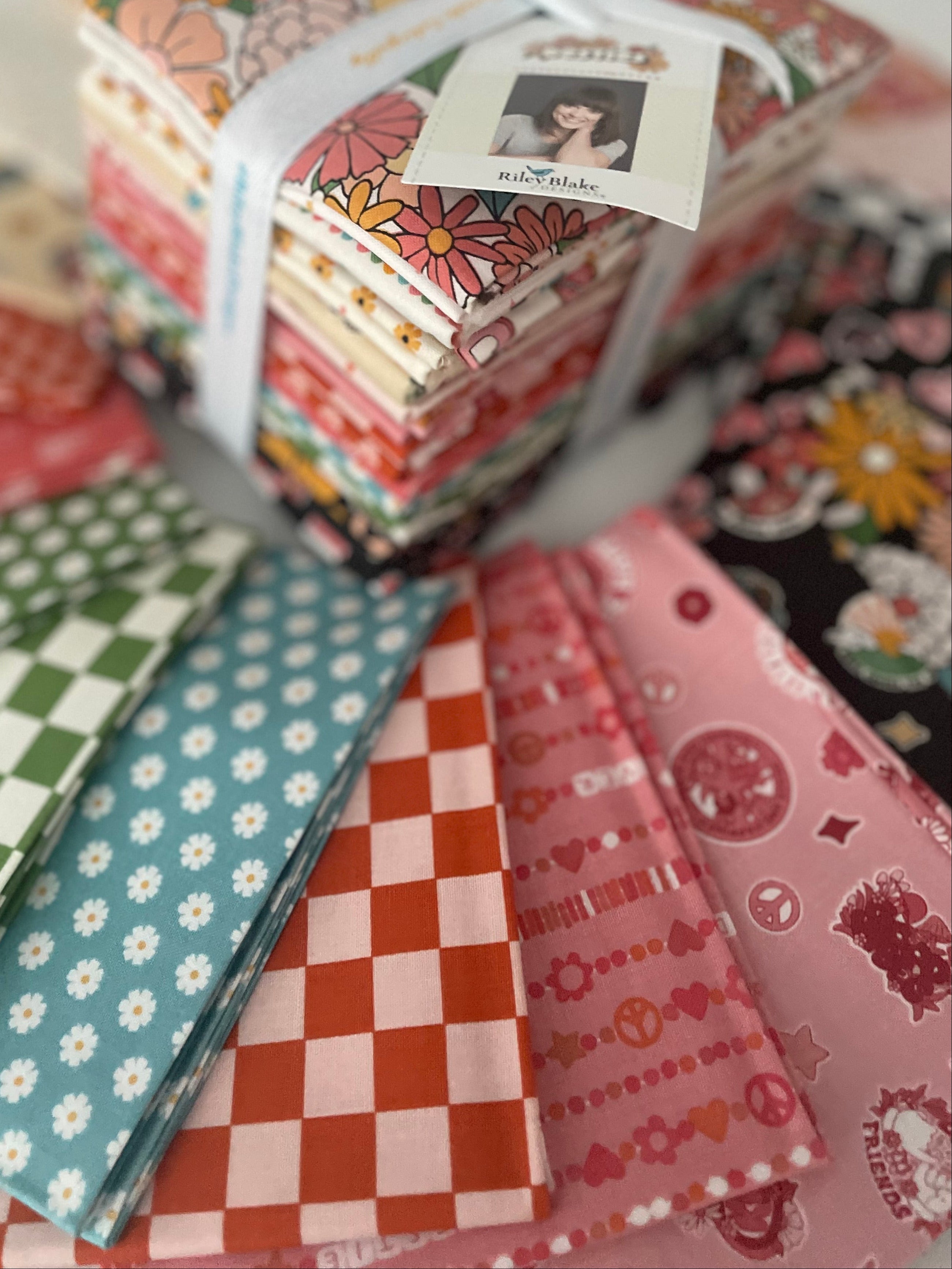 Stack of colorful fabric bundles with a visible brand tag on a white surface.