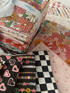 Collection of patterned fabric bundles with a white ribbon on a light background