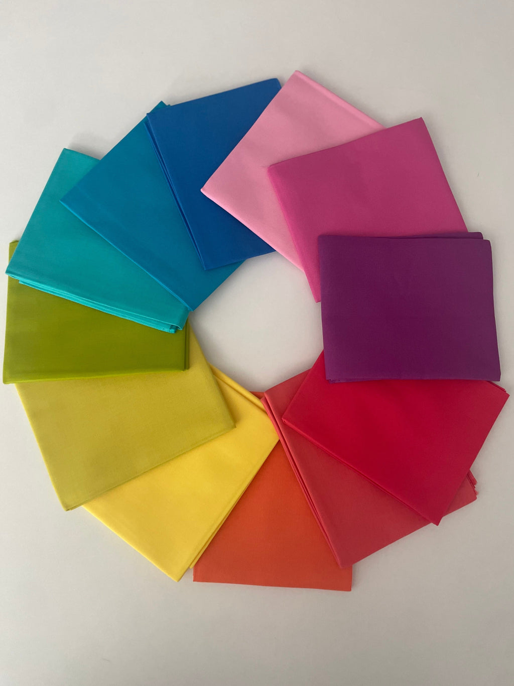 Colorful square cloths arranged in a circular pattern on a white background
