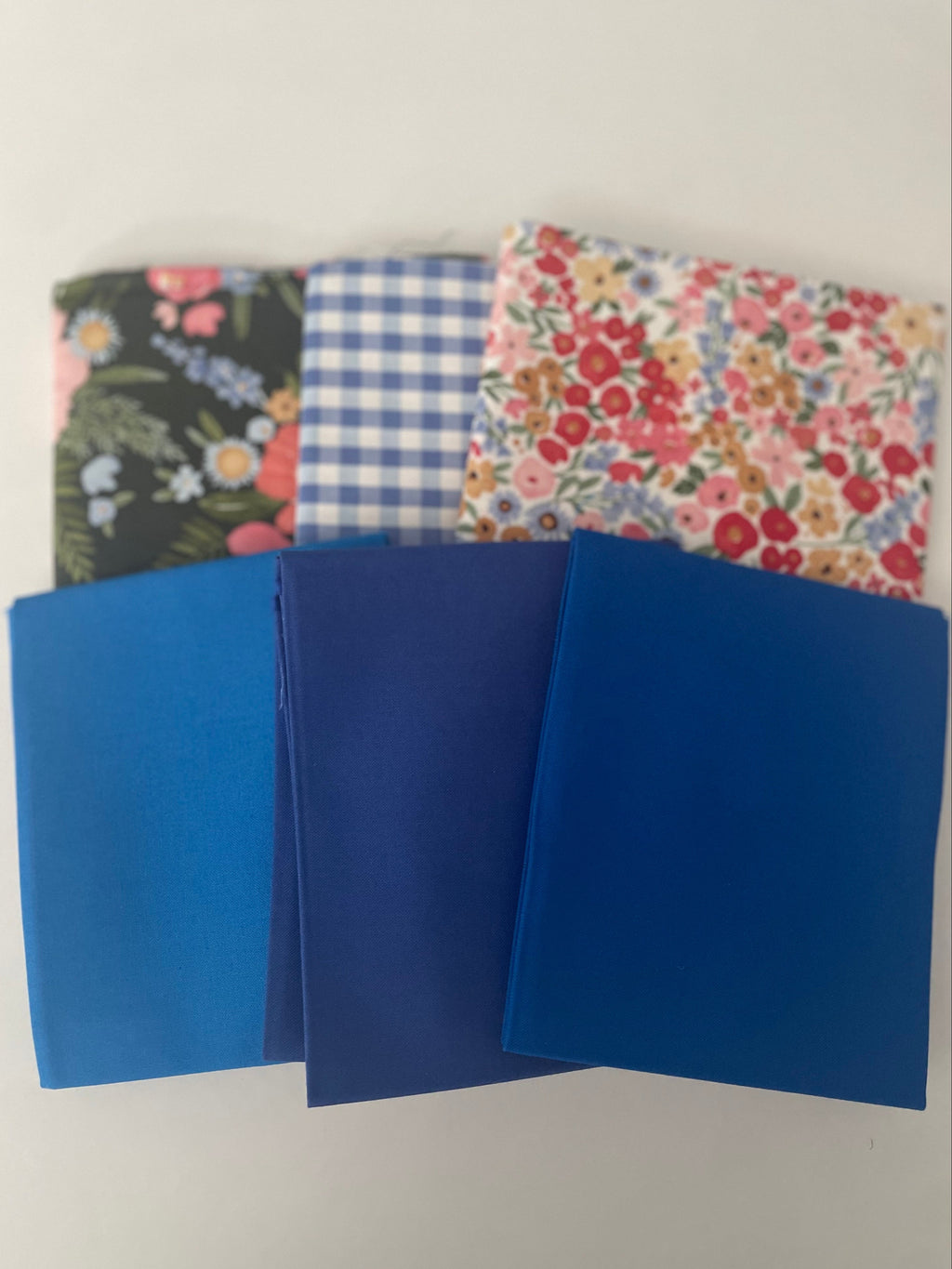 Three blue folders with floral and checkered covers on a white background