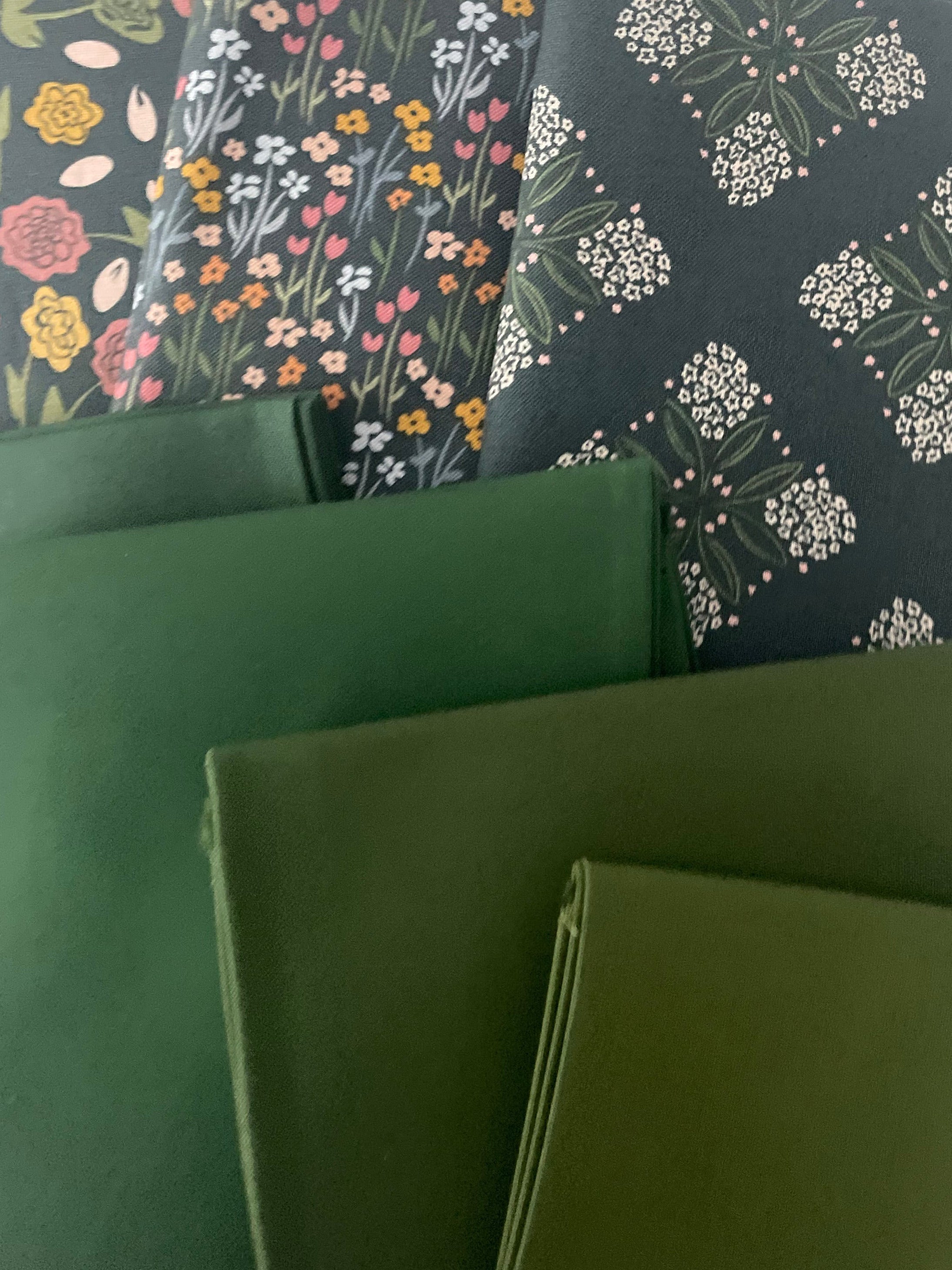 Green fabric swatches with floral patterns on a white background
