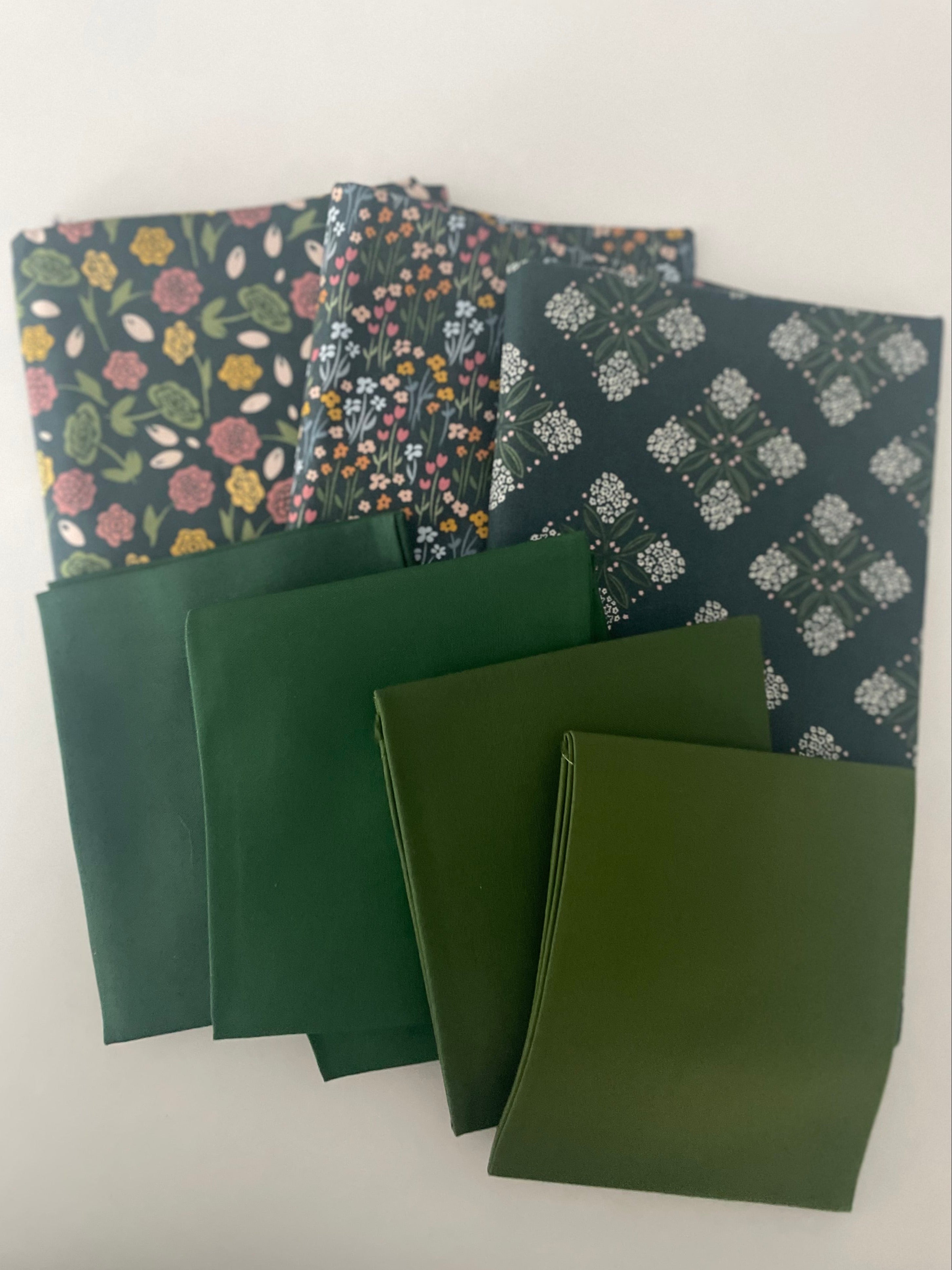 Set of green fabric swatches with floral and geometric patterns on a white background