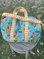 Floral-patterned bag with striped handles on a chair outdoors