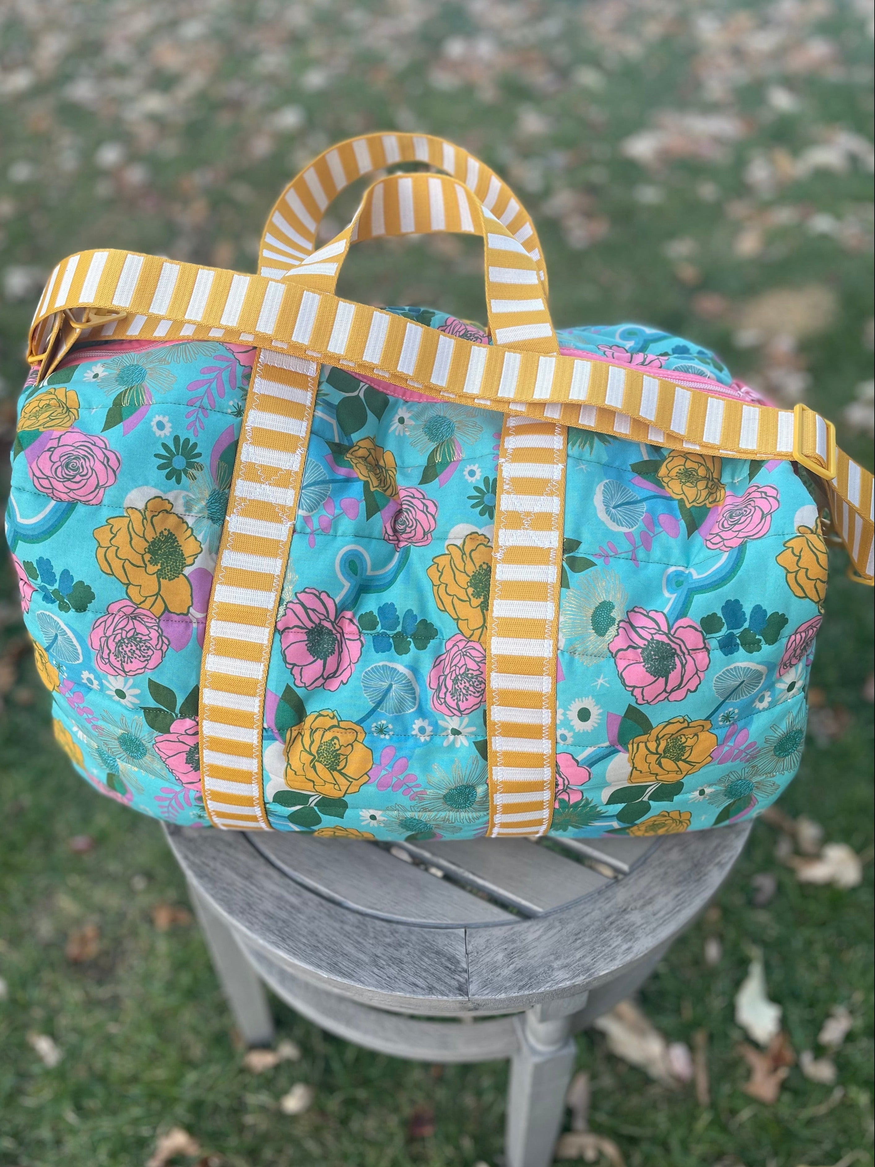 Floral-patterned bag with striped handles on a chair outdoors