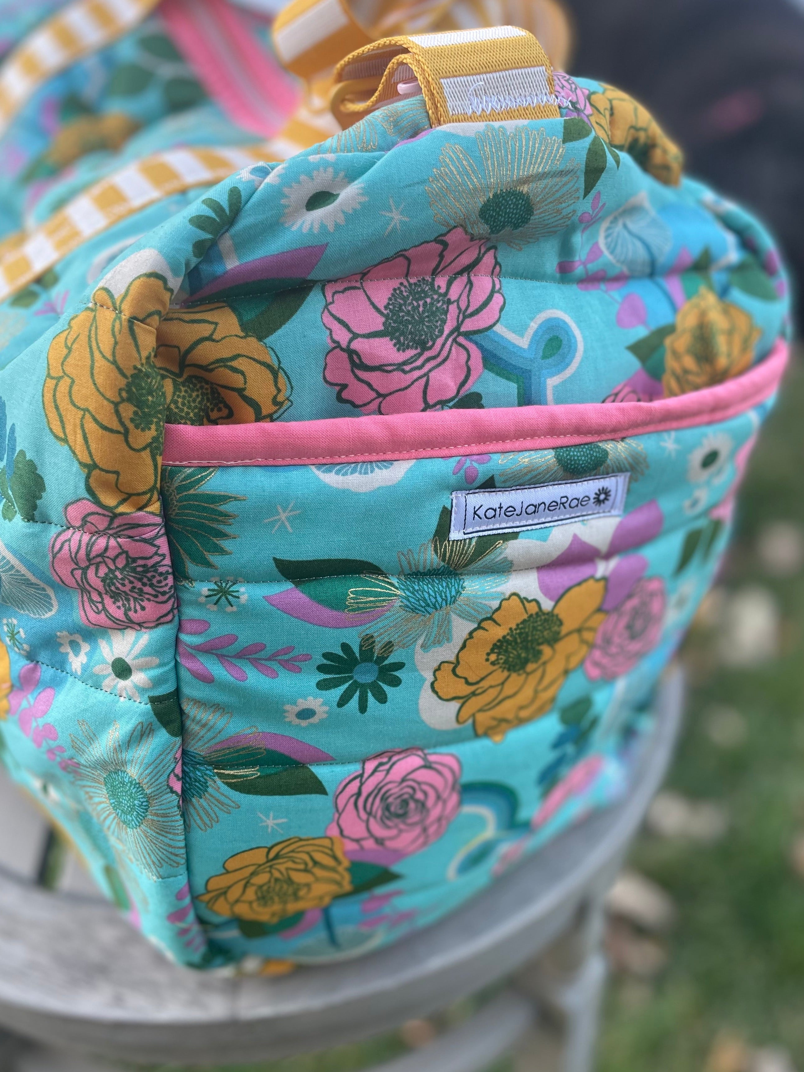 Floral-patterned cooler bag with pink zipper on a chair outdoors