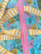 Colorful fabric bag with floral pattern and striped straps on a grassy background