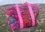 Two floral-patterned bags with colorful straps on a grassy surface.