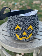 Fabric bowl with pumpkin pattern and face on a wooden surface