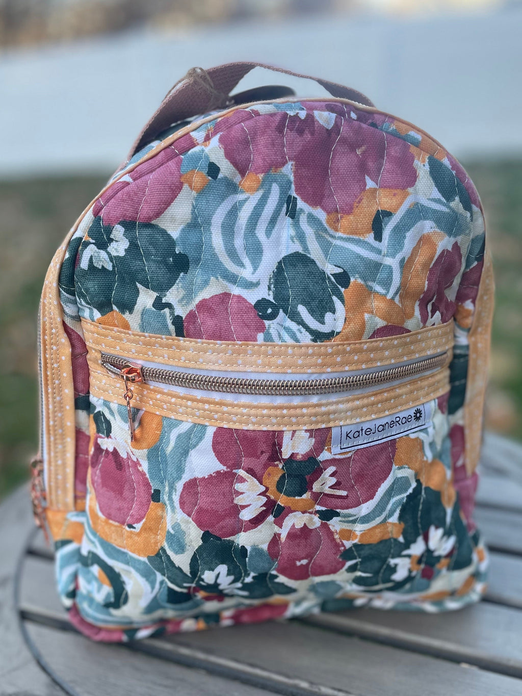 Floral-patterned backpack on a wooden surface with a blurred natural background