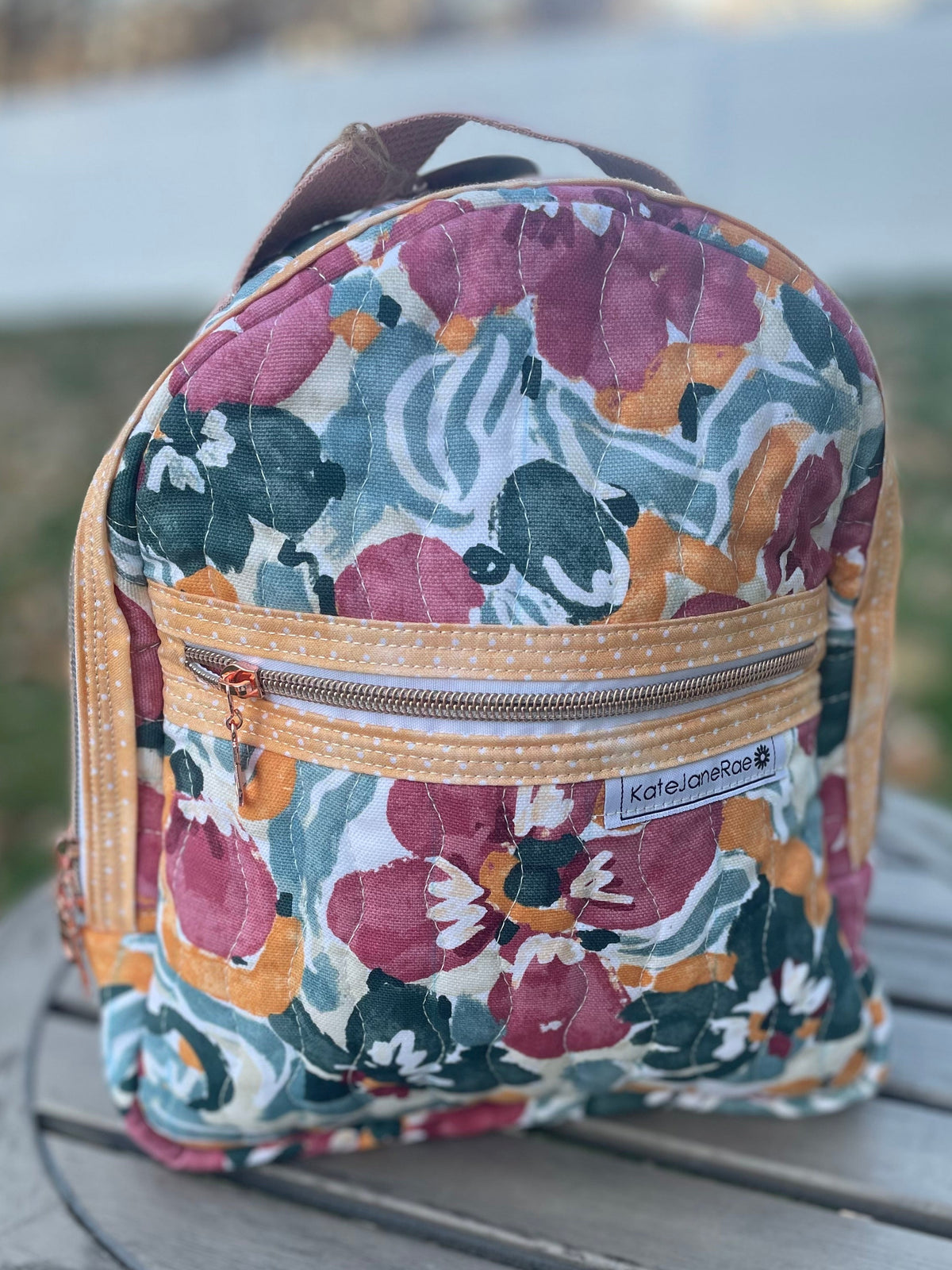 Floral-patterned backpack on a wooden surface with a blurred natural background