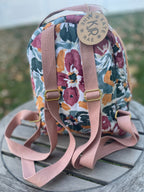 Floral-patterned backpack with pink straps on a wooden surface
