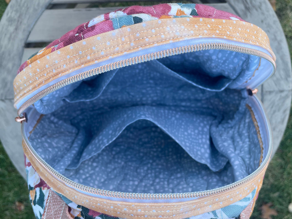 Backpack with floral pattern on the outside and blue interior lining.