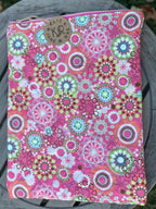 Pink fabric with colorful circular patterns on a wooden surface