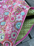 Colorful fabric pouch with floral pattern and pink zipper on a wooden surface