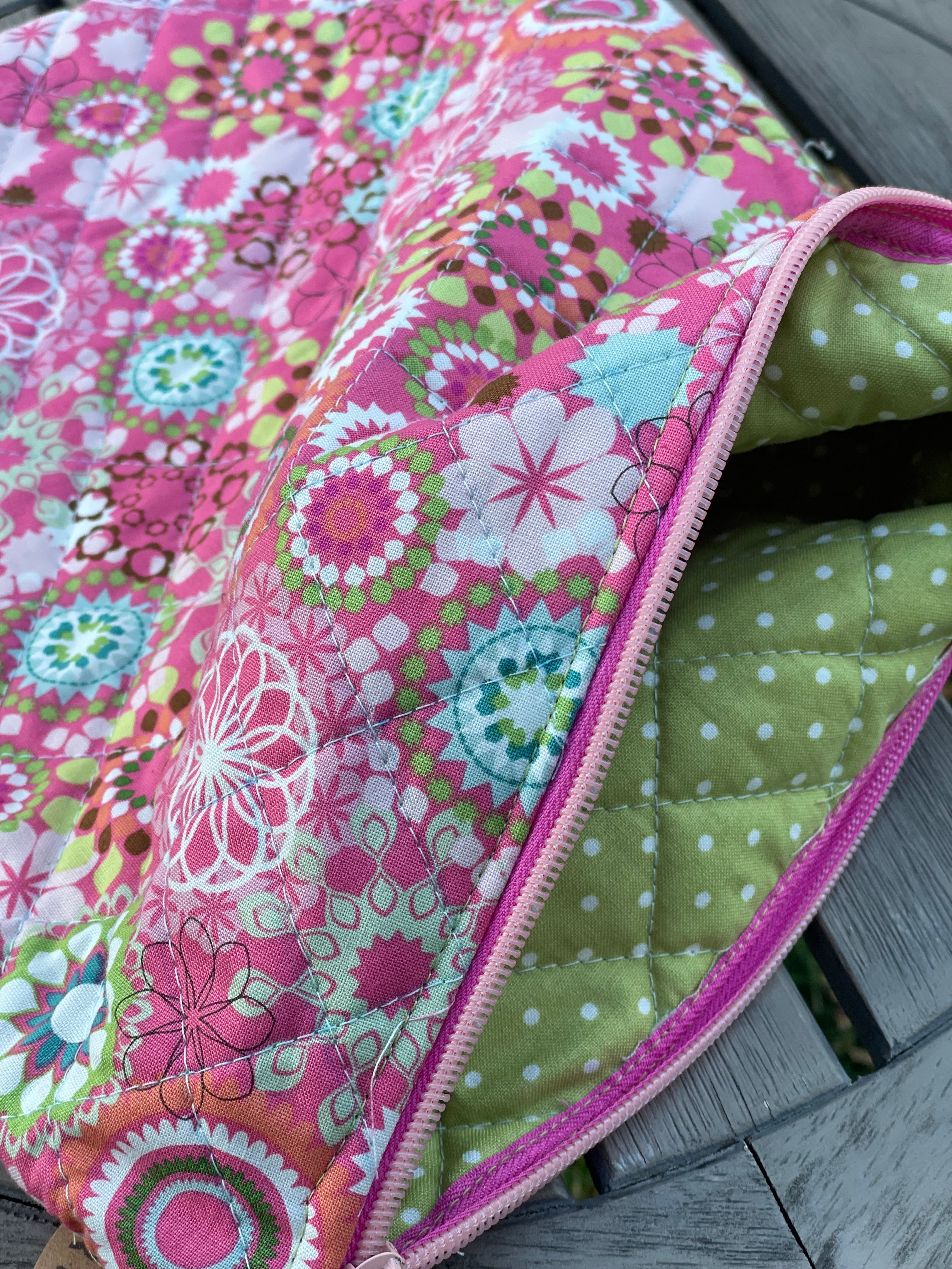 Colorful fabric pouch with floral pattern and pink zipper on a wooden surface