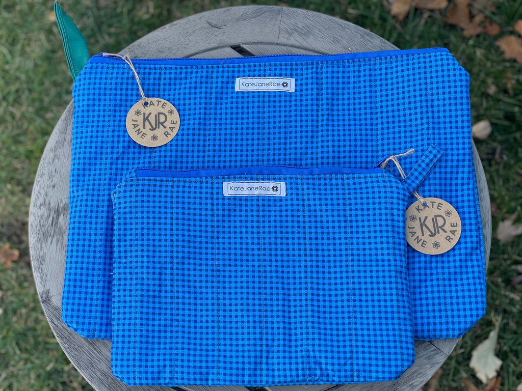 Blue oversized pouches with 'KR' branding on a gray surface outdoors.