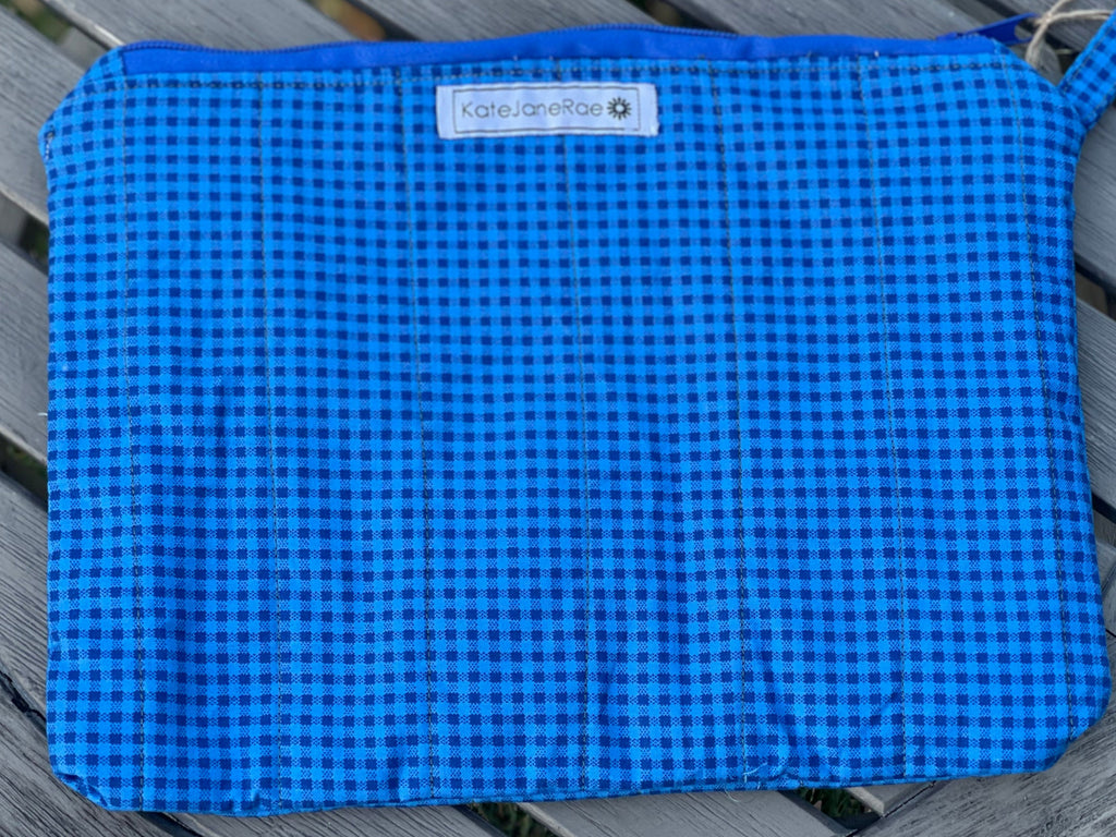 Blue checkered pouch on a wooden surface with a visible brand label.