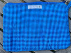 Blue checkered pouch on a wooden surface with a visible brand label.