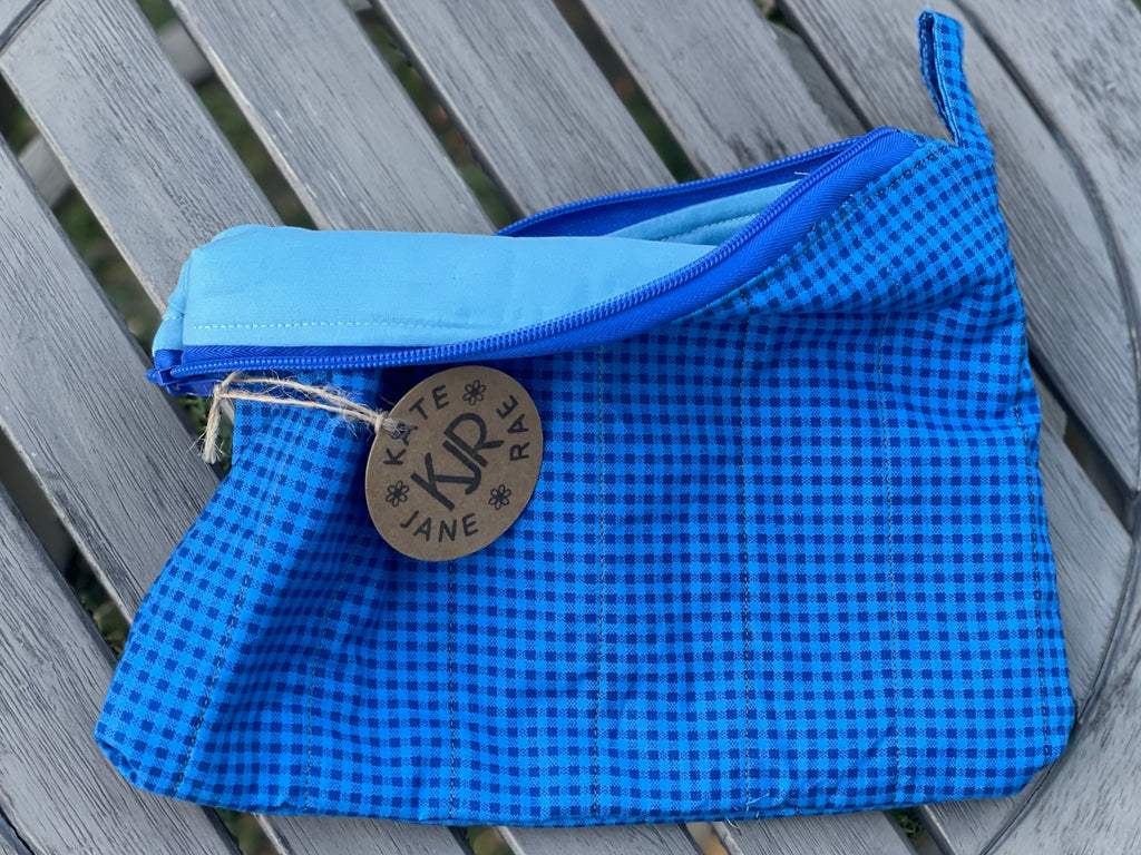 Blue checkered pouch with a brand logo on a wooden surface