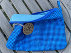 Blue checkered pouch with a brand logo on a wooden surface