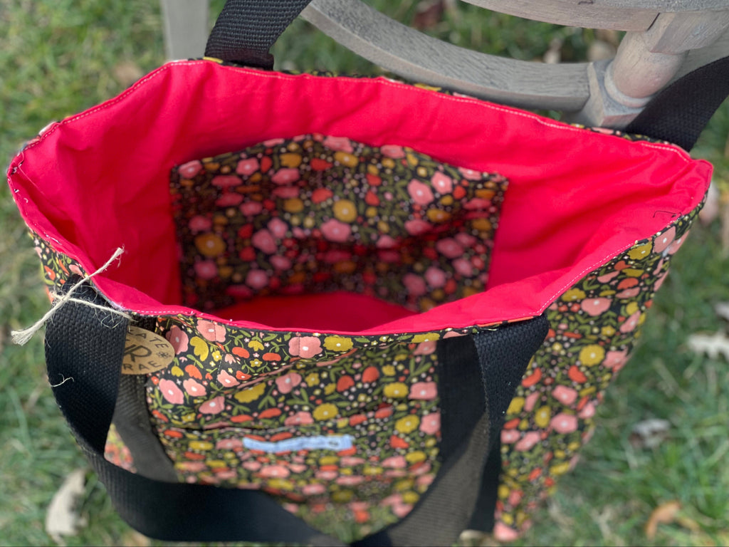 Floral-patterned bag with a red interior on a grassy background