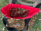 Floral-patterned bag with a red interior on a grassy background