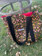 Floral-patterned bag with black straps on a grassy surface