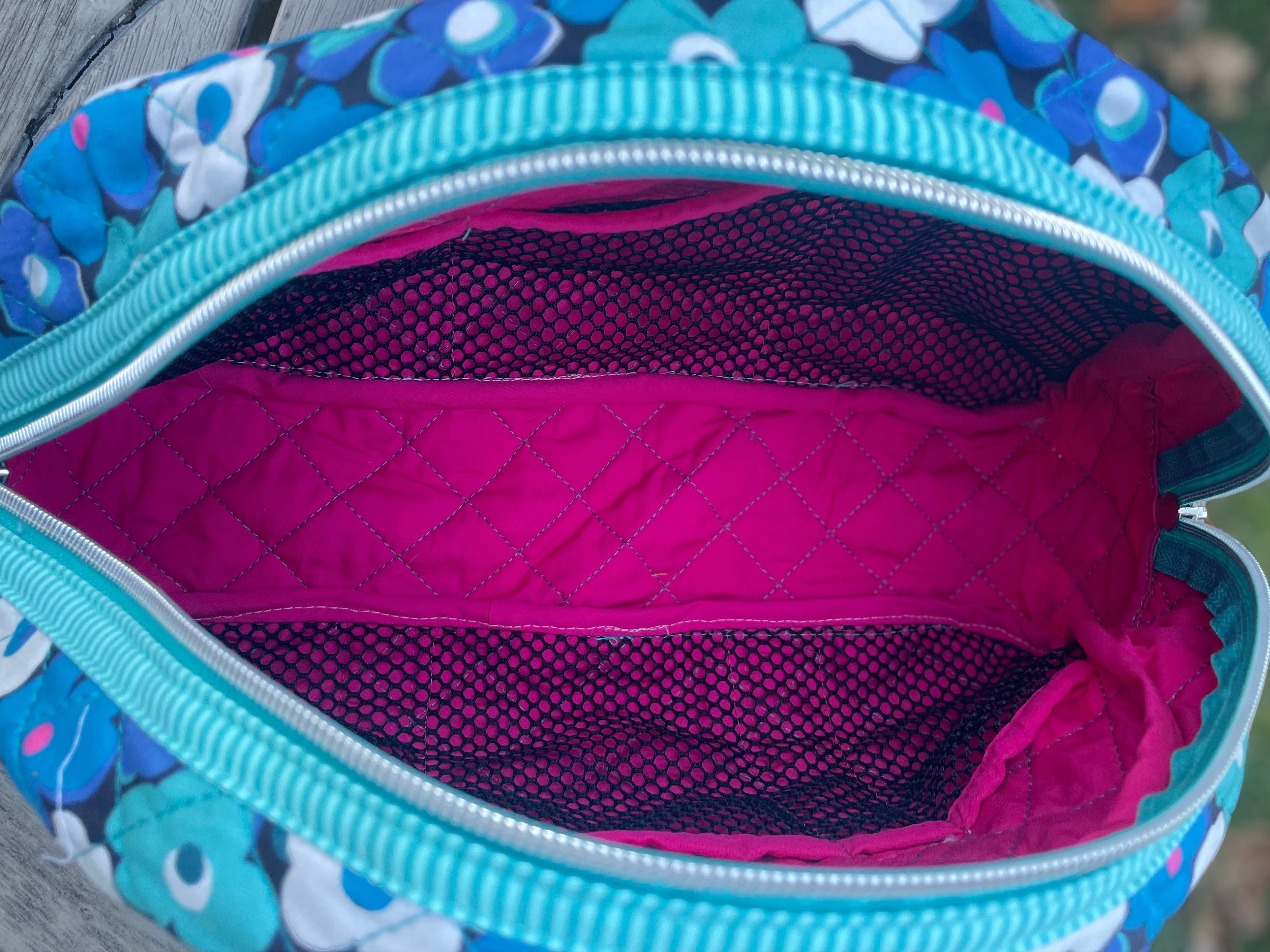 Floral-patterned bag with open zipper showing pink interior