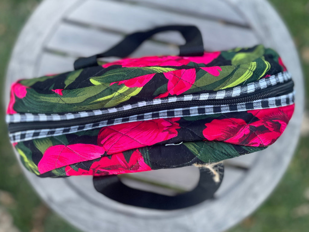 Floral-patterned bag with a black zipper on a white chair outdoors.