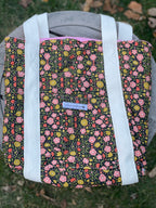 Floral-patterned bag with a visible brand label on a grassy background