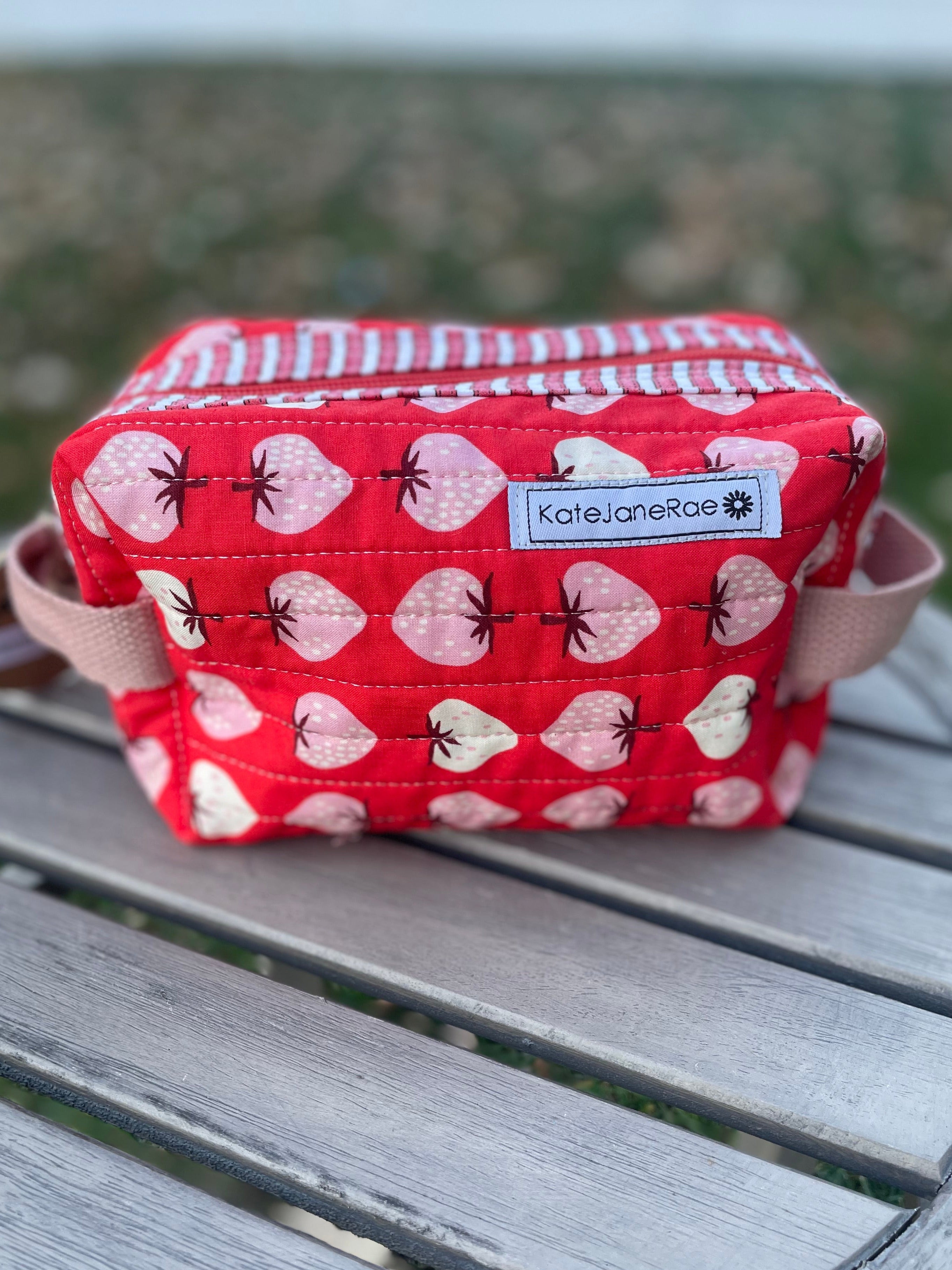 Red fabric pouch with pink heart pattern on a wooden surface