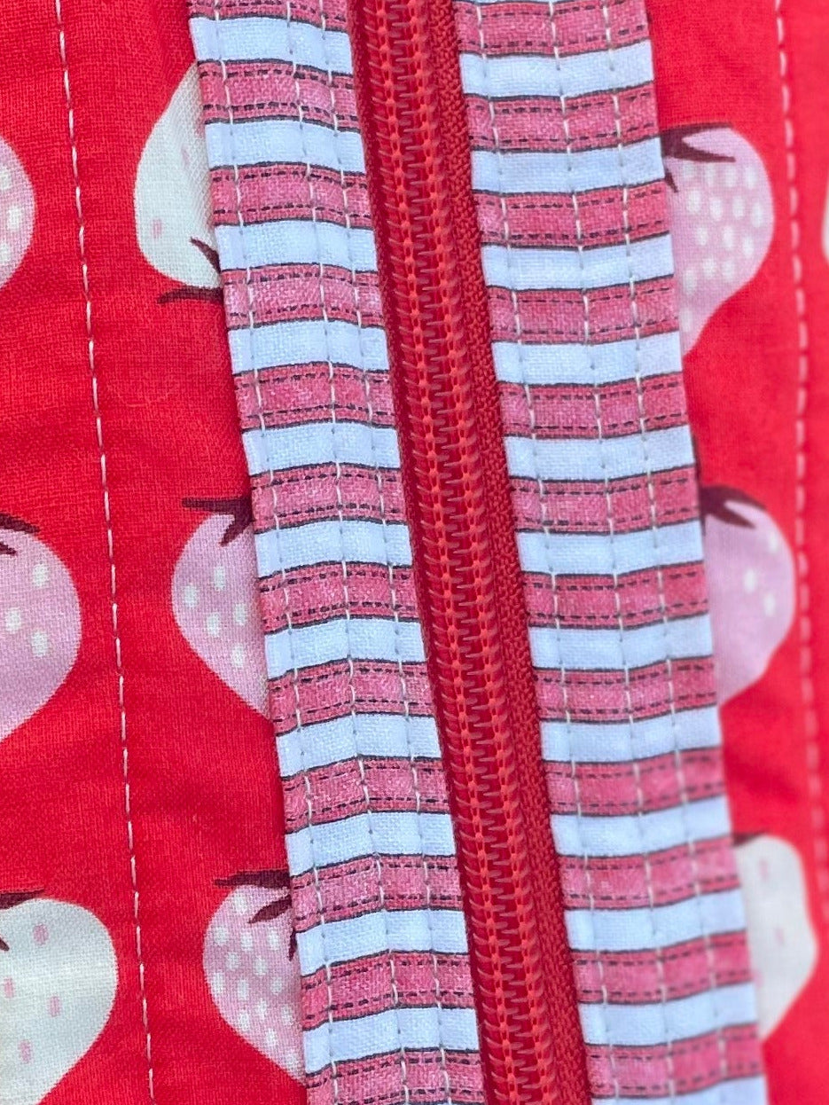 Red pouch with pink hearts and a zipper on a metal surface