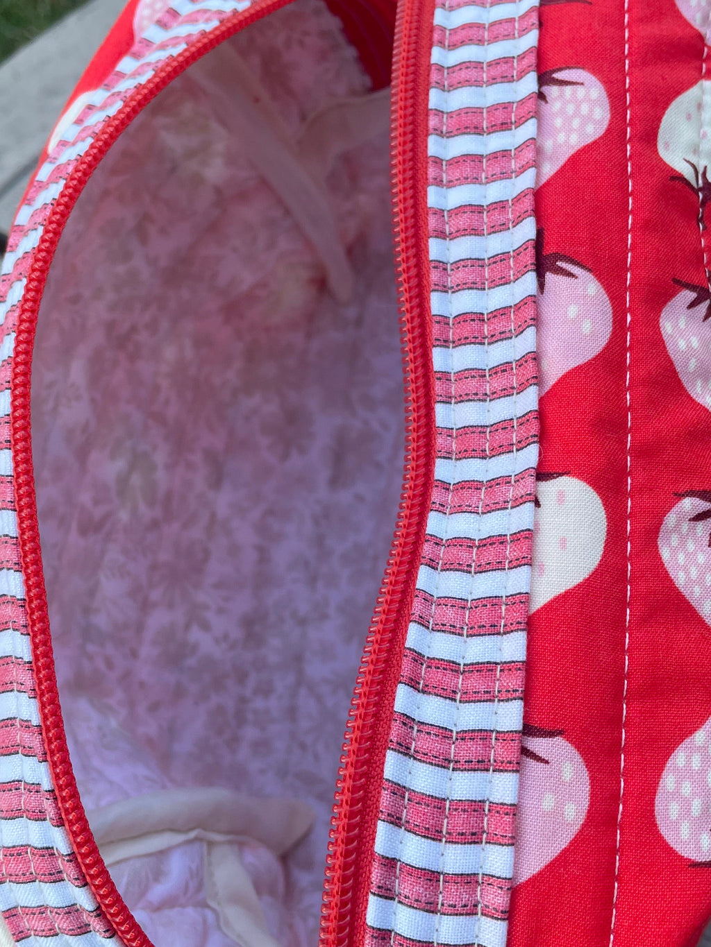 Red fabric pouch with pink floral pattern on a wooden surface