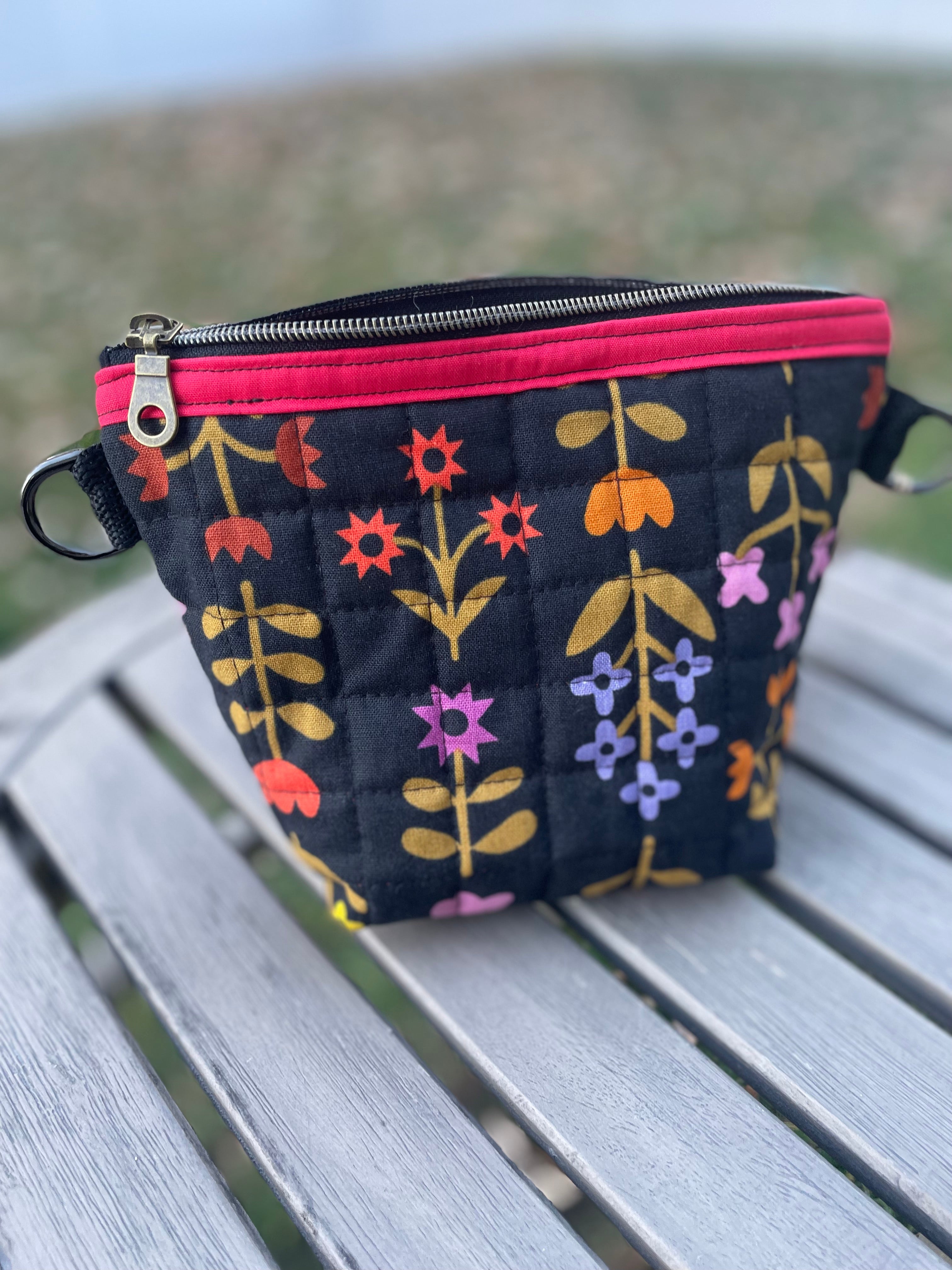 Floral-patterned pouch with a pink zipper on a wooden surface