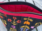 Floral-patterned pouch with red interior on a wooden surface