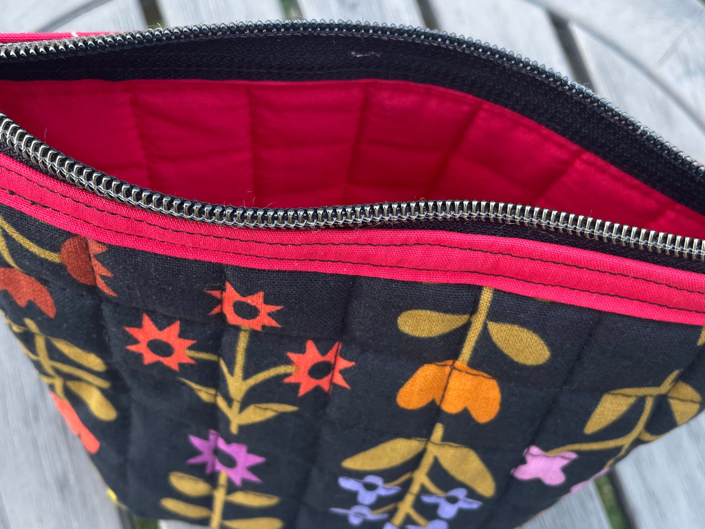 Floral-patterned pouch with red interior on a wooden surface