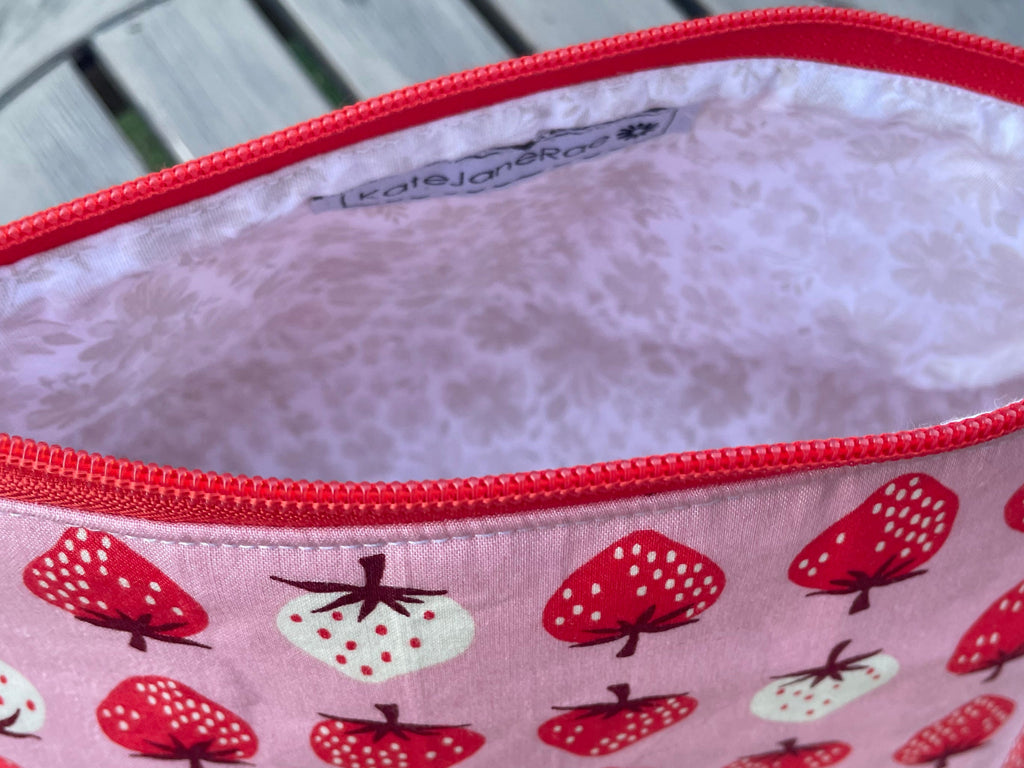 Fabric pouch with strawberry pattern on a wooden surface