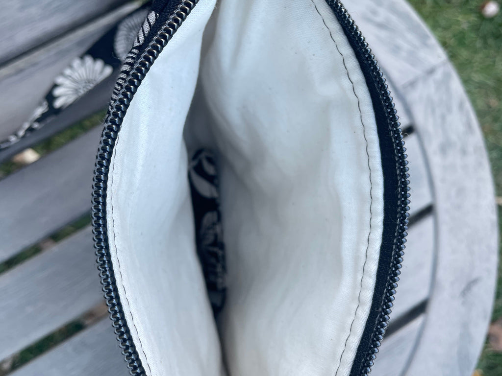 Close-up of a gray pouch with a black zipper on a wooden surface.