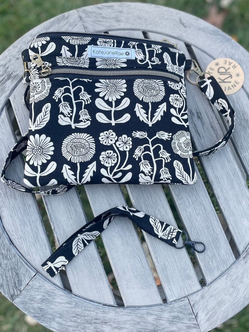 Black and white floral-patterned bag on a wooden stool outdoors