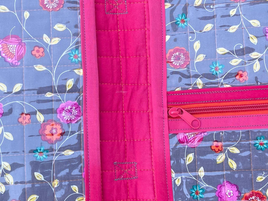 Floral-patterned organizer with pink trim on grass