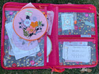 Embroidery kit with hoop and materials in a pink case on grass