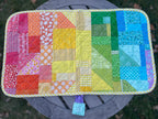 Colorful patchwork quilt on a wooden surface with a natural background