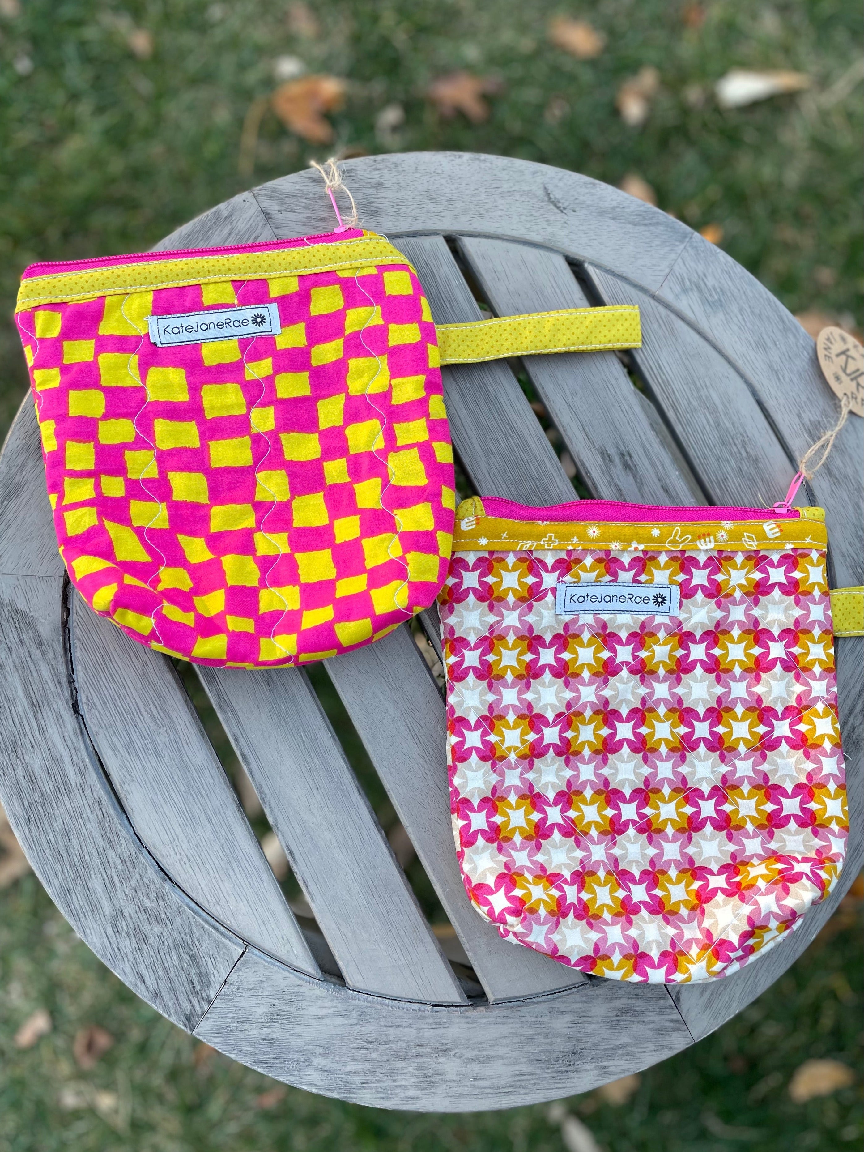 Two colorful pouches with checkered patterns on a wooden surface outdoors.