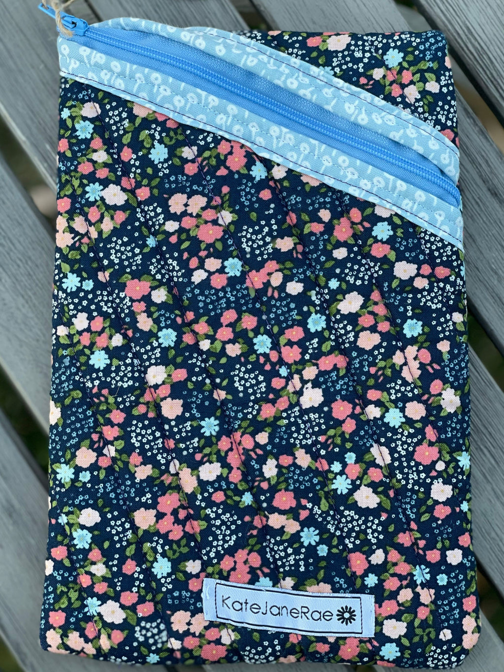 Floral-patterned notebook with a blue zipper on a wooden surface