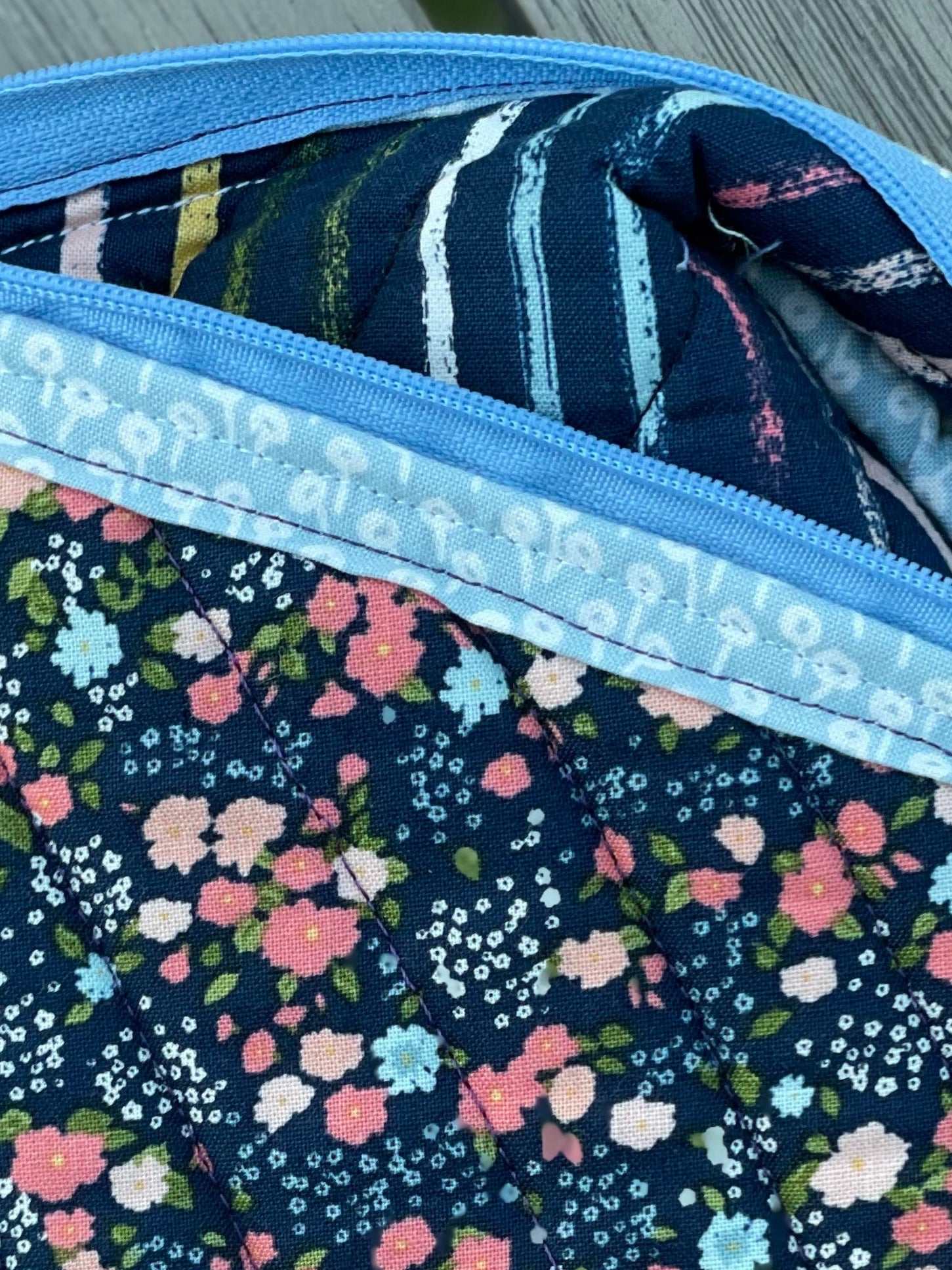 Floral-patterned pouch with a visible brand label on a wooden surface